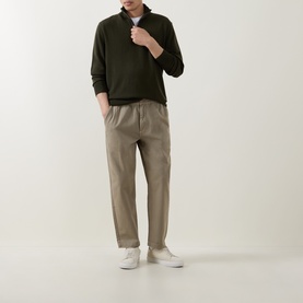 Model wearing Calvin Klein Monogram Logo Half-Zip Sweater in Olive Night, styled with taupe trousers and white trainers.