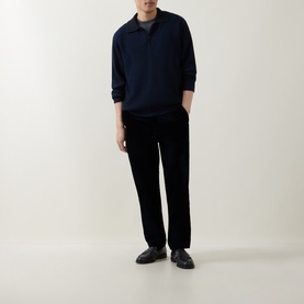 Model wearing Calvin Klein Badge Logo Textured Polo Sweater in Black, styled with black trousers and leather loafers.