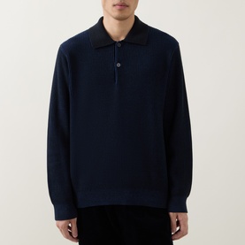 Model wearing Calvin Klein Badge Logo Textured Polo Sweater in black, featuring polo collar, two-button placket, long sleeves and ribbed trims.