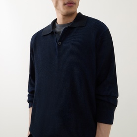 Model wearing Calvin Klein Badge Logo Textured Polo Sweater in black, featuring ribbed knit texture, polo collar, and long sleeves, styled over a