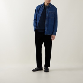 Model wearing Calvin Klein Badge Logo Textured Polo Sweater in Black, styled with blue denim overshirt, black trousers and black loafers.