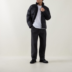 Model wearing Calvin Klein Graphic Logo T-Shirt in Bright White, styled with a black puffer jacket, dark trousers, and black leather shoes.