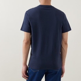 Model wearing Calvin Klein Graphic Logo T-Shirt in Blue Nights, rear view, crew neck, short sleeves, styled with blue jeans.