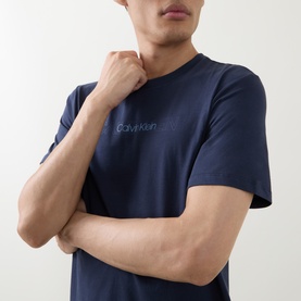Model wearing Calvin Klein Graphic Logo T-Shirt in Blue Nights, crew neck, short sleeves, contrast logo lettering on chest