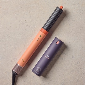 Dyson Coanda 2x Ceramic Apricot hair styler in apricot and purple, shown with detachable barrel attachment on stone surface