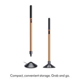 Dyson hair styling tools in copper and black displayed upright in compact magnetic storage stands, shown at two heights.