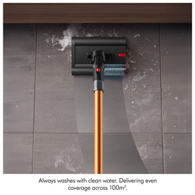 Cordless vacuum cleaner with gold wand and wide floor head cleaning tiled floor, showing even water coverage across surface.