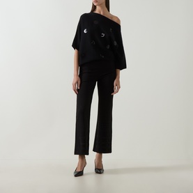 Model wearing Joseph Ribkoff Sequin Embellished Knitted Sweater in black with boat neck, styled with black wide-leg trousers and heels.