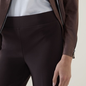 Model wearing Joseph Ribkoff Trousers in mocha, styled with a white top and zip-up jacket. Slim-fit silhouette with elasticated waistband.