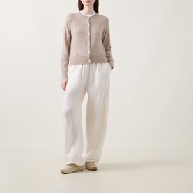 Model wearing Lucy Nagle The Everyday Cardigan in Light Weight Beige, fine knit with round neck and logo disc detail, styled with white wide-leg