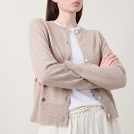 Model wearing Lucy Nagle The Everyday Cardigan in light weight beige, round neck fine knit with logo disc buttons, styled with white tee and cream
