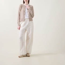 Model wearing Lucy Nagle The Everyday Cardigan in light beige fine knit with round neck and ribbed trims, styled with white wide-leg trousers.