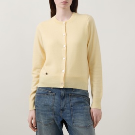 Model wearing Lucy Nagle The Everyday Cardigan in Primrose, round neck, logo disc detail, styled with blue jeans