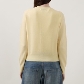 Model wearing Lucy Nagle The Everyday Cardigan in Primrose, fine knit, back view, styled with blue wide-leg jeans