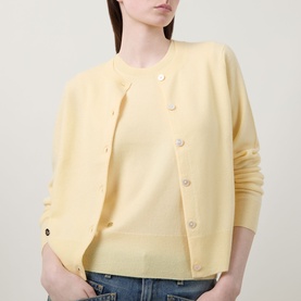 Model wearing Lucy Nagle The Everyday Cardigan in Primrose, fine knit with round neck and logo disc detail, styled over matching yellow knit top