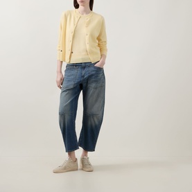 Model wearing Lucy Nagle The Everyday Cardigan in Primrose, styled with mid-blue tapered jeans and beige trainers.