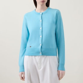 Model wearing Lucy Nagle The Everyday Cardigan in Bambino blue, fine knit with round neck, white buttons, and ribbed trims, styled with white trousers