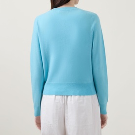 Model wearing Lucy Nagle The Everyday Cardigan in Bambino blue, fine knit, ribbed trims, long sleeves, back view, styled with white wide-leg trousers