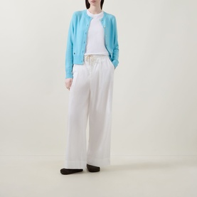 Model wearing Lucy Nagle The Everyday Cardigan in Bambino blue, round neck, fine knit, styled with white wide-leg trousers and white top.