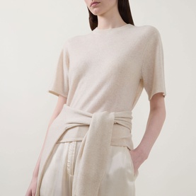 Model wearing Lucy Nagle The Cashmere Top in Pearl, crew neck, short sleeves, styled with cream wide-leg trousers and tied knit waist detail.