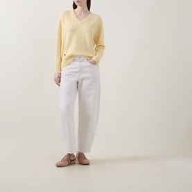 Model wearing Lucy Nagle The Elevated Cashmere Sweater in Primrose, V-neck fine knit, styled with white wide-leg jeans and nude flat mules