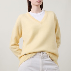Model wearing Lucy Nagle The Elevated Cashmere Sweater in Primrose, V-neckline, dropped shoulders, styled with white jeans and layered tee.