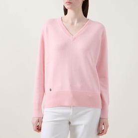 Model wearing Lucy Nagle The Elevated Cashmere Sweater in Crystal Rose, V-neck fine knit with logo disc, styled with white trousers.