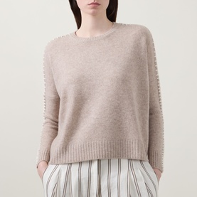 Model wearing Lucy Nagle The Stitch Cashmere Sweater in Light Weight Beige with crew neck, stitch shoulder detail, styled with striped trousers.