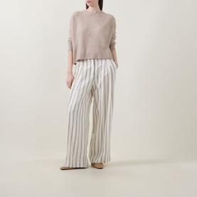 Model wearing Lucy Nagle The Stitch Cashmere Sweater in Light Weight Beige with white striped wide-leg trousers and nude flat shoes.