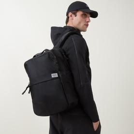 Model carrying Lululemon Everyday Backpack 21L in Black/Graphite Grey, styled with black hoodie and cap