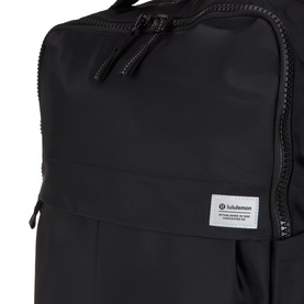 Lululemon Everyday Backpack 21L in Black/Graphite Grey, close-up of top zip compartment with logo patch detail