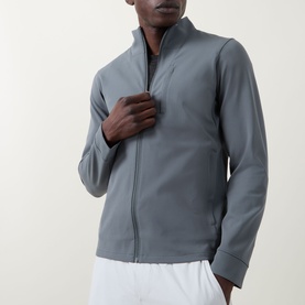 Model wearing Lululemon Sojourn Jacket in Onyx Grey, with zip-up stand collar, styled with white trousers