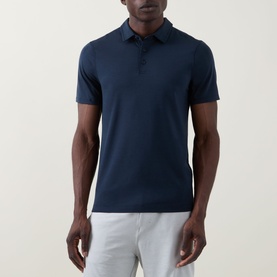 Model wearing Lululemon Reg Polo in True Navy, styled with light grey trousers