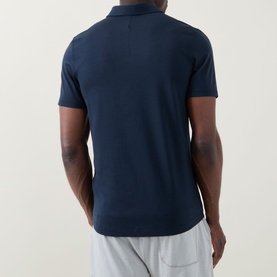 Model wearing Lululemon Reg Polo in True Navy, rear view, styled with light grey shorts