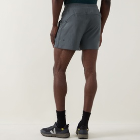 Model wearing Lululemon Pace Breaker Shorts 5" in Onyx Grey, rear view, styled with black ankle socks and trail trainers.