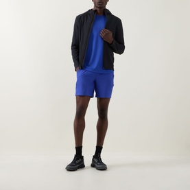Model wearing Lululemon Pace Breaker Linerless Shorts 7" in Beach Ball Blue, styled with a black zip-up jacket and black trainers.