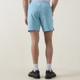 Model wearing Lululemon seafoam performance shorts, rear view, styled with white socks and black trainers.