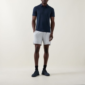Model wearing Lululemon shorts in Heathered Vapor/Heathered Silver Drop, styled with a navy polo shirt and dark trainers.