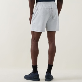 Model wearing Lululemon shorts in Heathered Vapor/Heathered Silver Drop, shown from behind, styled with black socks and navy trainers.