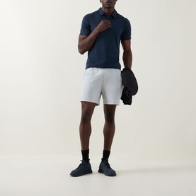Model wearing Lululemon shorts in Heathered Vapor/Heathered Silver Drop, styled with a navy polo shirt and dark trainers.