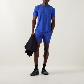 Model wearing Lululemon Beach Ball Blue performance T-shirt and matching shorts, styled with black trainers, carrying a black jacket.