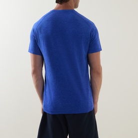 Model wearing Lululemon Metal Vent Tech Short-Sleeve T-Shirt in Ocean Wave/Beach Ball Blue, back view, styled with navy shorts.