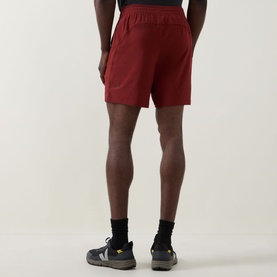 Model wearing Lululemon Cranberry Charm performance shorts, shown from behind, styled with black socks and grey trail trainers.