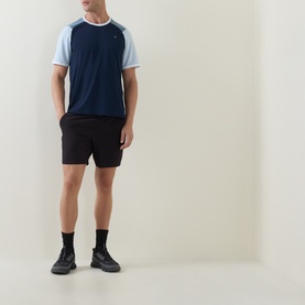 Model wearing Lululemon UV-Protective Textured Mesh Tennis Shirt in Club Blue/Steel Blue, styled with black shorts and chunky trainers.
