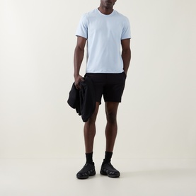 Model wearing Lululemon Starch Blue T-shirt with black shorts, carrying black jacket, styled with black socks and chunky trainers