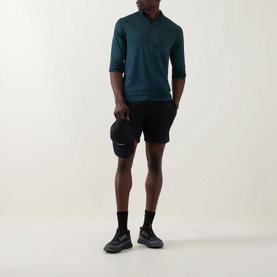 Model wearing Lululemon Metal Vent Short Sleeve T-Shirt in Green Cove/Club Blue, styled with black shorts, socks, and trainers, holding a cap.