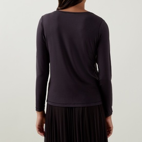 Model wearing Tuzzi Dark Chocolate long-sleeve viscose shirt, rear view, styled with a black pleated skirt.