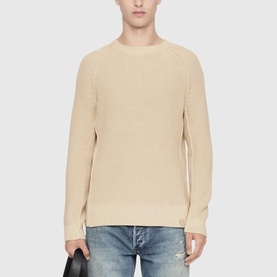 Model wearing All Saints ecru white ribbed crew neck knit sweater, styled with blue jeans.