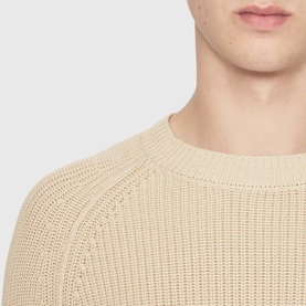 Model wearing All Saints ecru white chunky knit crew neck jumper, close-up showing ribbed texture and neckline detail.