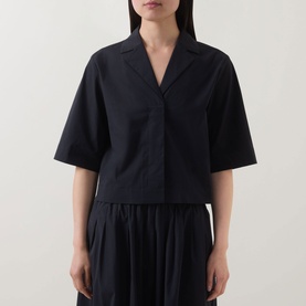 Model wearing Marc O Polo Woven Cropped Blouse in black with notch lapel collar and half-length sleeves, styled with a pleated black skirt.